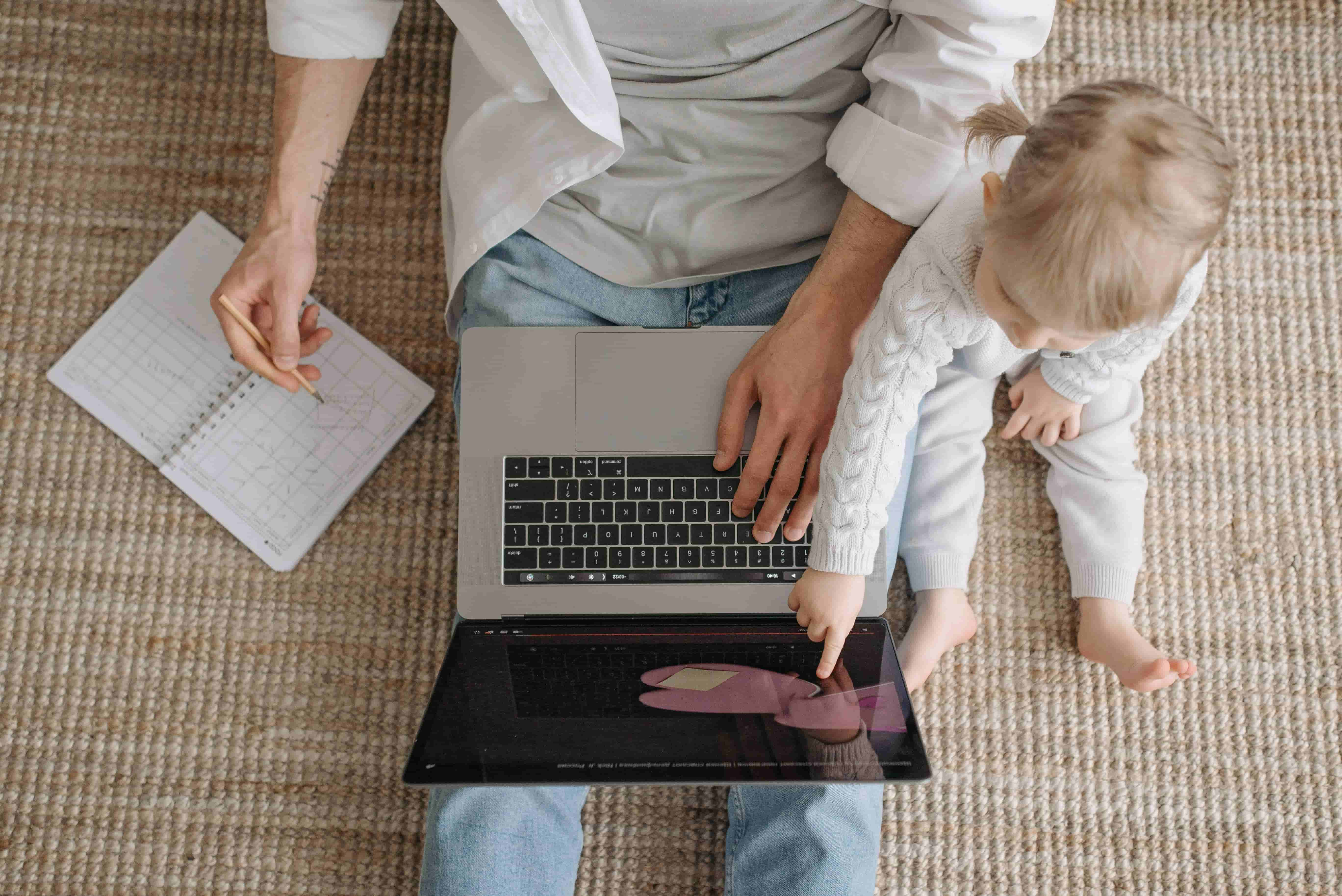 Image d'une personne travaillant avec son jeune enfant assis à côté